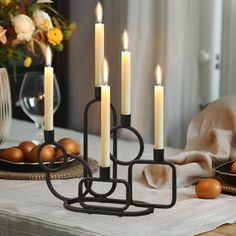 a candle holder with five candles on top of a table next to eggs and flowers