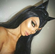 a woman with long black hair wearing a cat ears headband and green eyeliners