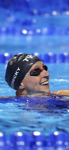 a woman swimming in a pool with goggles on her head and wearing a swim cap