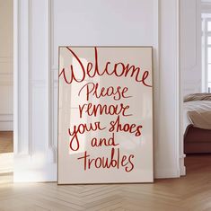 a welcome sign in front of a white wall with red writing on it that reads, welcome please remove your shoes and troubles