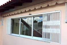 an open window on the side of a building that has shutters and blinds in it