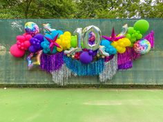 balloons and streamers spell out the word 10 on a tennis court with trees in the background