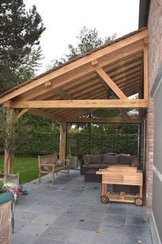 a patio covered in wooden furniture next to a brick building