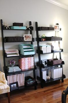 a living room filled with lots of shelves next to a chair and table in front of a window