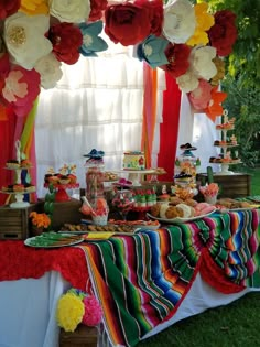 a colorful dessert table with paper flowers on it