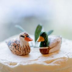 two small figurines sitting on top of a cake