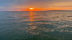 the sun is setting over the ocean as seen from a boat on the water's surface