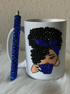 a white coffee mug with blue beads on it and a pen in the cup next to it