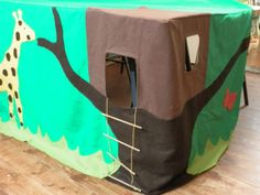 a tent with a giraffe painted on the front and back sides, sitting on top of a hard wood floor