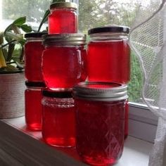 jars filled with red liquid sit on a window sill