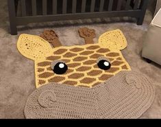 a crocheted giraffe rug on the floor next to a crib