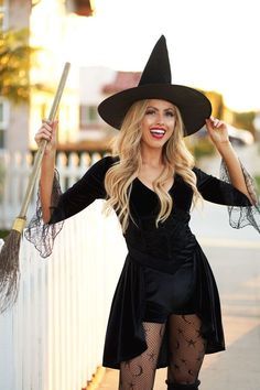 a woman dressed as a witch holding two brooms