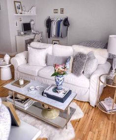 a living room filled with white furniture and lots of pillows on top of it's couch