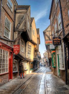 two people are walking down an old street