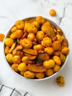 a white bowl filled with nuts on top of a marble counter next to a towel