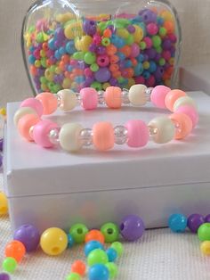 there is a box with some beads on it and a glass jar full of colorful beads