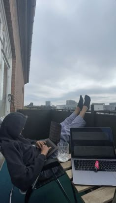 a person laying on top of a roof with their feet up in the air while using a laptop computer