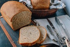 two loaves of bread sitting on top of a cutting board next to a knife and fork