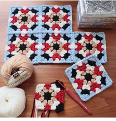 there are crocheted squares and yarns on the table