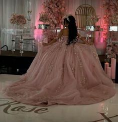 a woman in a pink dress is sitting on the floor with flowers and candles around her