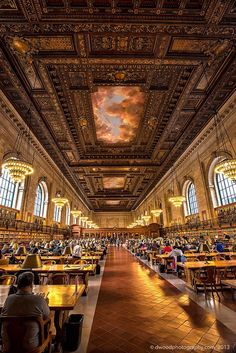 people are sitting at tables in a large room with high ceilings and ornate paintings on the walls