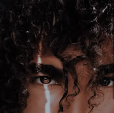 a man with curly hair is staring at the camera and has tears on his face