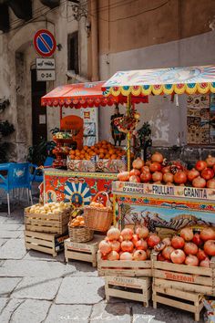 an outdoor fruit stand with oranges and apples