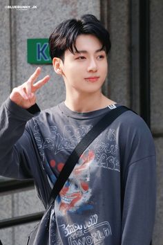 a young man making the peace sign with his hand while standing in front of a building