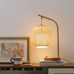 a table lamp sitting on top of a wooden shelf next to a cup and books