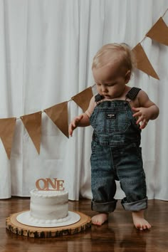 a baby standing in front of a cake