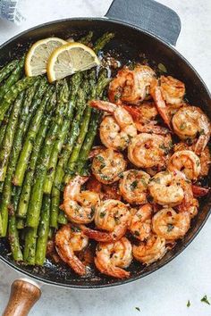 shrimp and asparagus in a skillet with lemon wedges on the side