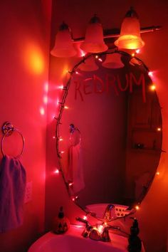 a bathroom sink under a lighted mirror with the word redrum on it's side