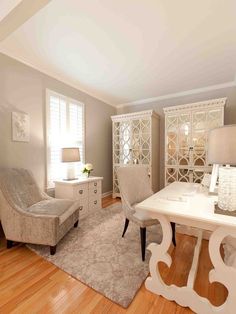 a living room filled with furniture and a white table in front of a chair on top of a hard wood floor