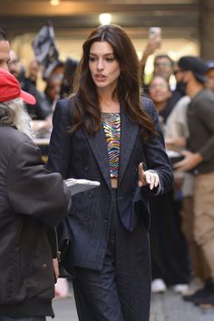 a woman in a suit is walking down the street with her hand on her hip