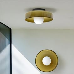 two circular lights hanging from the ceiling in a room with white walls and flooring