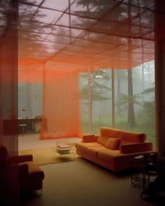 a living room filled with furniture and lots of windows covered in orange sheer fabric covering the walls