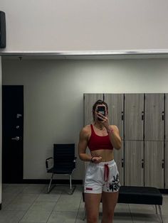 a woman taking a selfie in front of lockers with her cell phone up to her ear