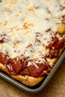 a square pizza sitting on top of a pan covered in cheese and pepperoni sauce