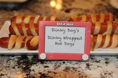 a sign that says skinnyy dog's slinky wrapped hot dogs on a plate