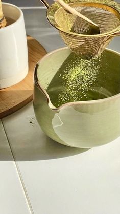 two bowls filled with green liquid on top of a table next to chopsticks