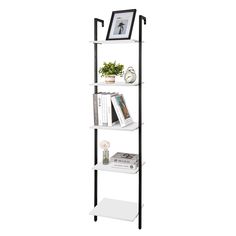 a black and white book shelf with books on the top, two pictures hanging above it