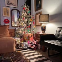 a living room with a christmas tree in the corner and pictures on the wall behind it