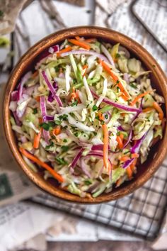 a wooden bowl filled with coleslaw and carrots on top of a table