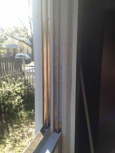 an open window with the blinds partially closed and sunlight coming through it, in front of a house