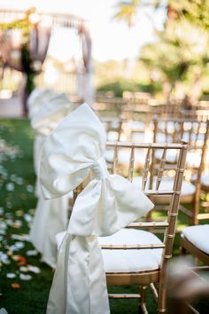 an image of a wedding ceremony with white chairs and bows on the back of them