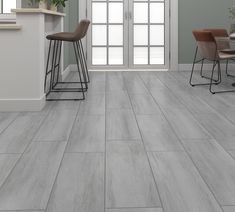 a kitchen with grey tile floors and white walls, two bar stools next to the counter