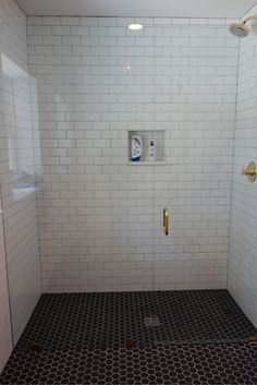 a bathroom with black and white tile on the floor, shower stall door and toilet