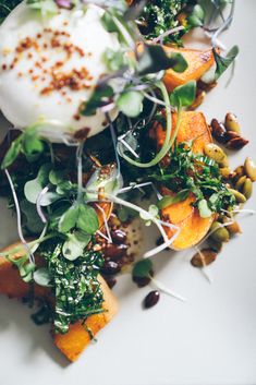 a white plate topped with lots of veggies and an poached egg