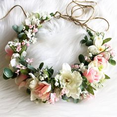 a flower crown is laying on top of a white furnishing with flowers and leaves