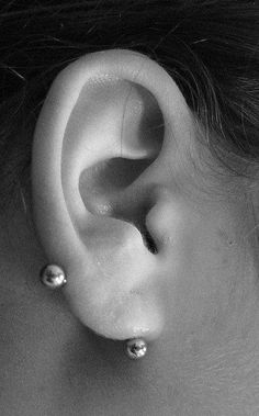 a close up of a person's ear with two piercings on the side